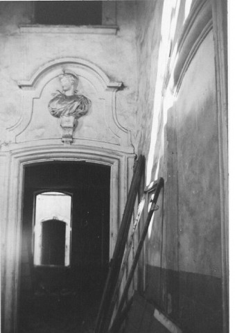 Intérieur d'immeuble ancien, un buste de pierre orne le dessus d'une porte